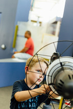 a boy child standing in front of a fan 
