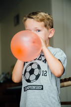 a boy child blowing up a balloon 