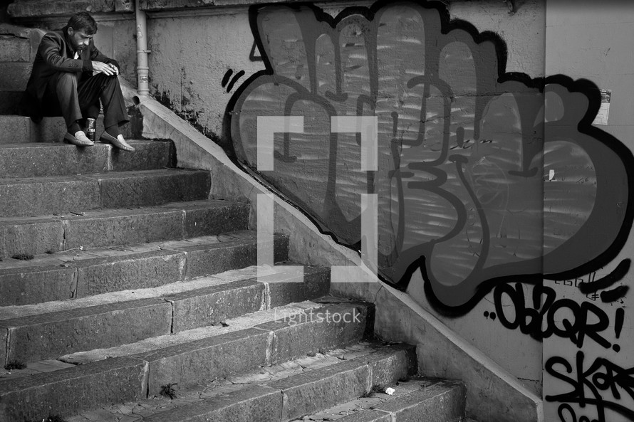 Man on concrete steps near graffiti wall