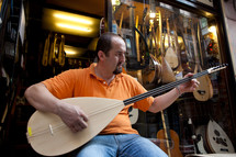 Turkish man playing Saz outside music store
