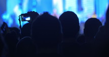 Crowd at a concert with a person holding up a digital camera.