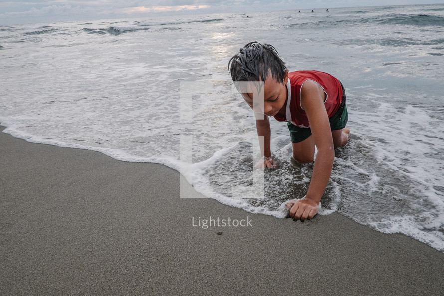 a boy playing in the sand on a beach