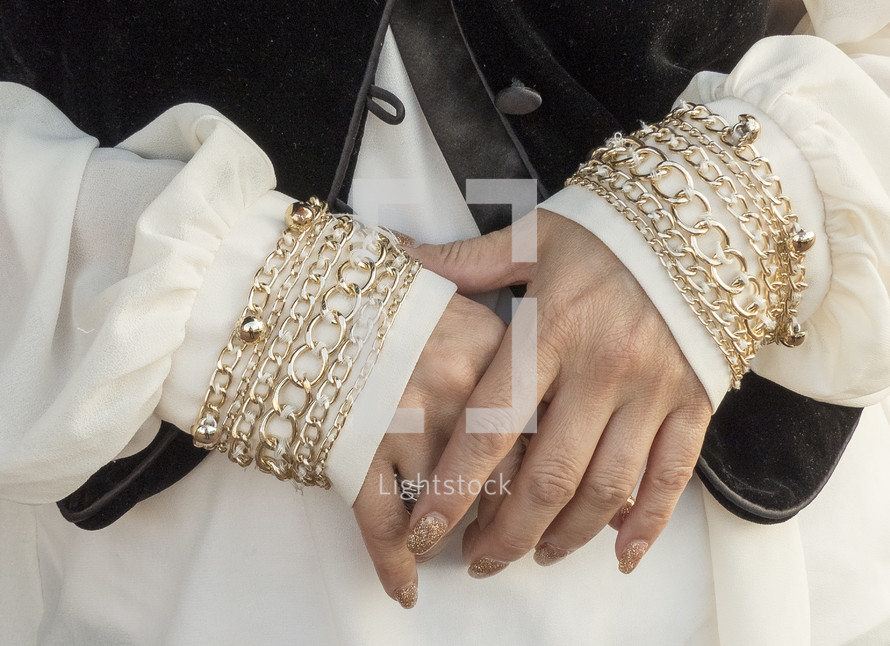 closeup of woman's hands - gold bracelet-like trim on cuffs and painted nails 