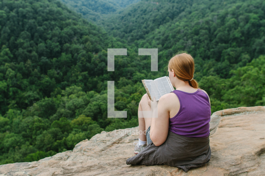 woman reading a Bible on a mountaintop 