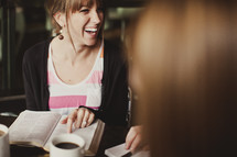 woman smiling pointing to the Bible during a Bible study