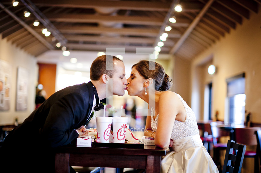 Bride and groom eating at fastfood restaurant