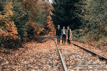 friends standing in the middle of train tracks 