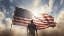 Rear view of a man holding the American flag against cloudy sky
