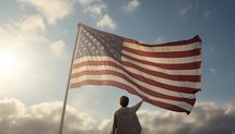 Rear view of man waving american flag against blue sky with clouds