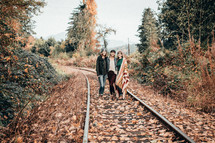 young women standing in the middle of train tracks 