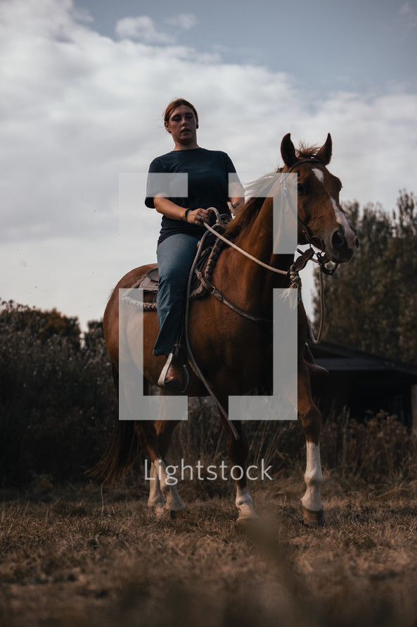 Horse riding woman on a brown stallion, western style saddle horseback rider