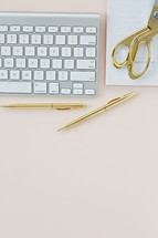 computer keyboard, gold pen, gold scissors, and notepad 