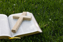cross and open Bible in the grass 