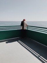 man standing on a pier looking out at the water below 