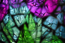 abstract stained glass montage with blurred foreground grout and translucent glass showing focused stained glass mosaic beyond