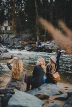 women looking across a river at a cabin 