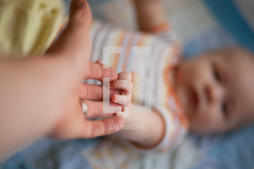 parent and infant holding hands