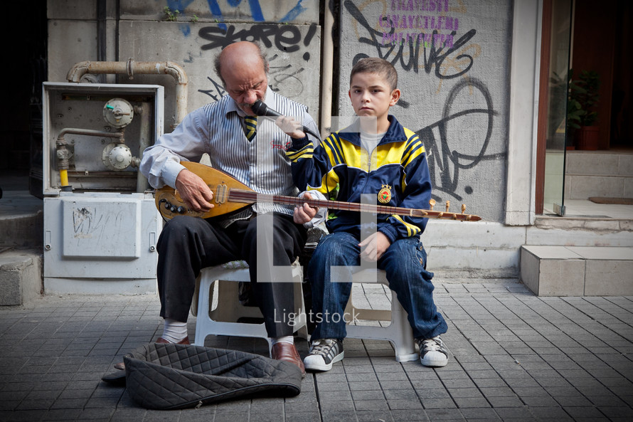 man and boy street musicians playing a sax