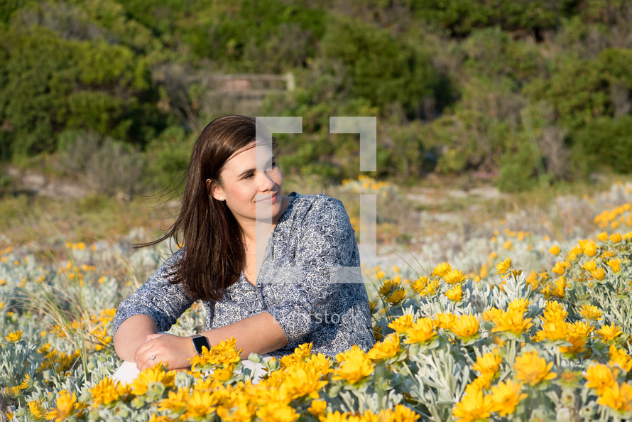 a woman sitting in a field of yellow flowers 