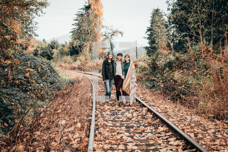 young women standing in the middle of train tracks 