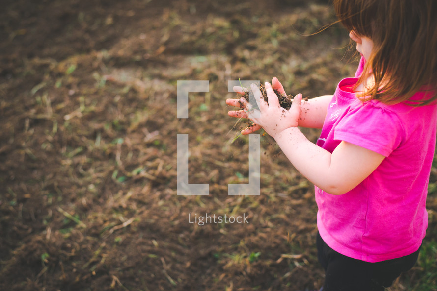 a toddler girl playing with dirt 