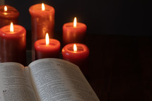red candles burning near a Bible 
