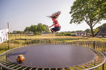 a girl child jumping on a trampoline 