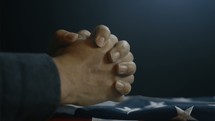 Praying with folded hands over the American flag.  