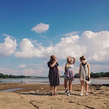 Three women on the banks of a lake.