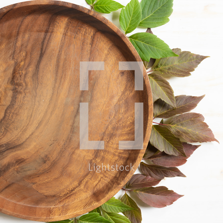 teak tray with red and green leaves on a white wood background 