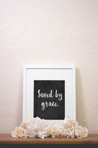 chalk words saved by grace in a frame and flowers 