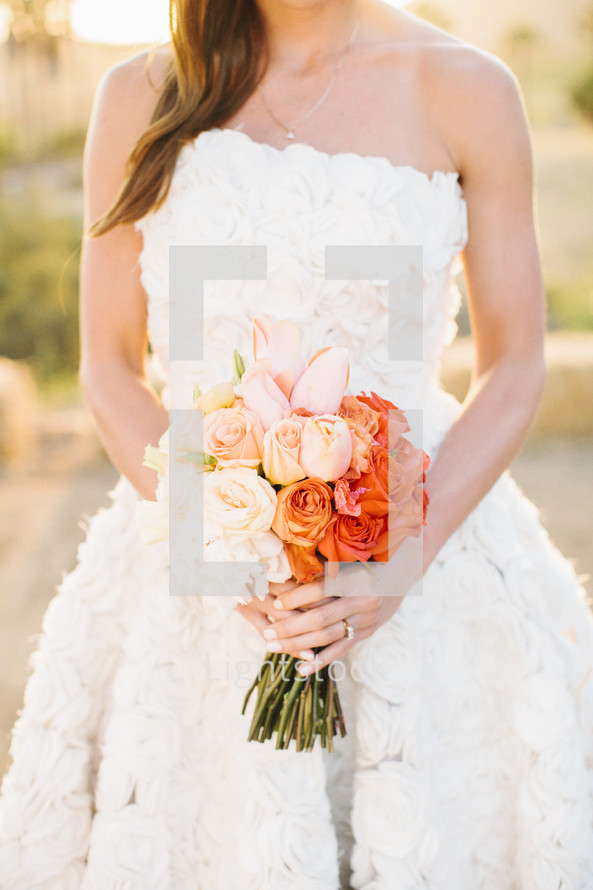 torso of a bride holding a bouquet