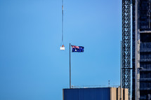 worker hanging from a crane fixing a flag on a flagpole in Australia 