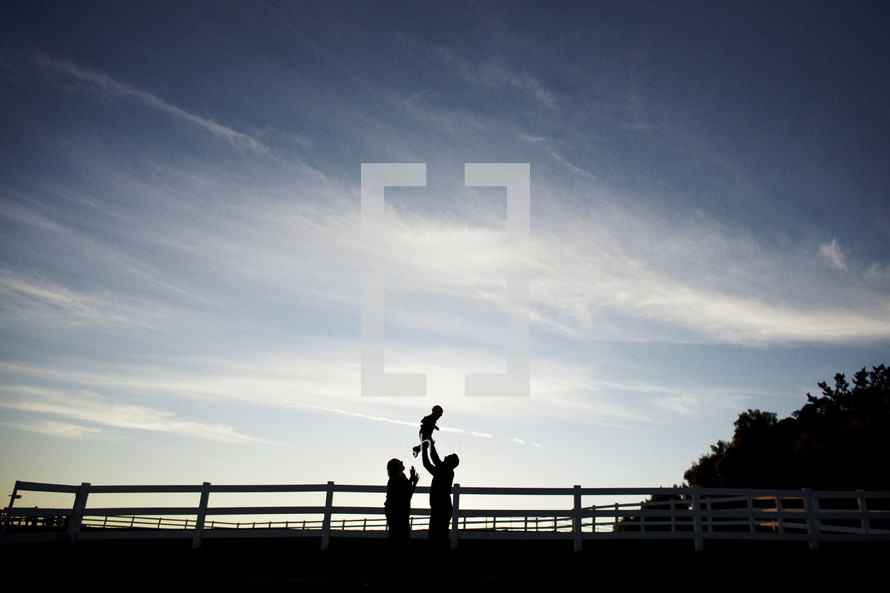 silhouette of a mother and father holding up their child