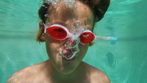 Boy in goggles blowing bubbles underwater