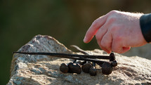 Long nails for crucifixion placed on a rock taken by a Roman soldier's hand
