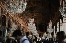 crowds of people under a hallway of chandeliers in Paris 