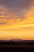 Vivid yellow sunrise over silhouette mountain peak range vertical