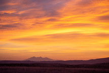 Colorful sunrise clouds over distant mountain range silhouette