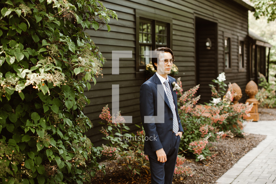 groom standing outdoors in front of a house 