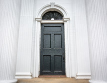 Black painted door on church building with transom and white column pillars