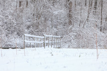 Snowy scene of wooden footbridge leading to the woods