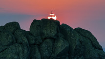Silhouette of a cross on mountain at sunset