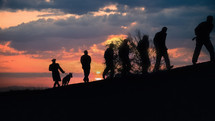 Prisoners with a guard and dog at sunset
