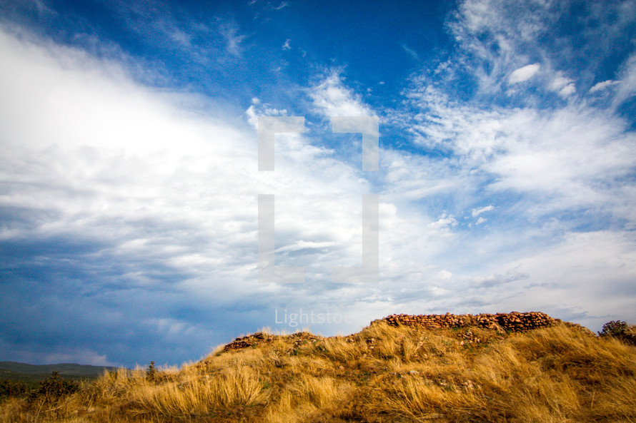 clouds over a hill with tall grass