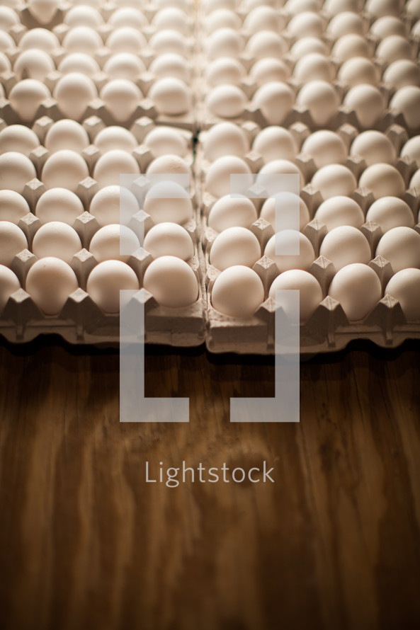 Cartons of white eggs on a wood table.