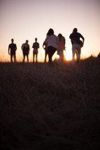 people outdoors in a field at sunset 