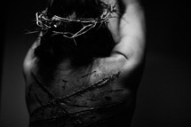 The suffering of Christ -- a beaten Jesus wearing His crown of thorns while bound to the cross by ropes.