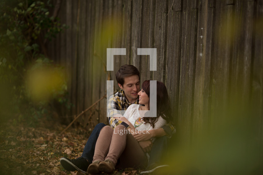 Couple hugging beside a wooden fence