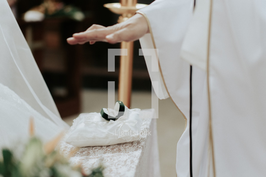 a priest blessing wedding rings 